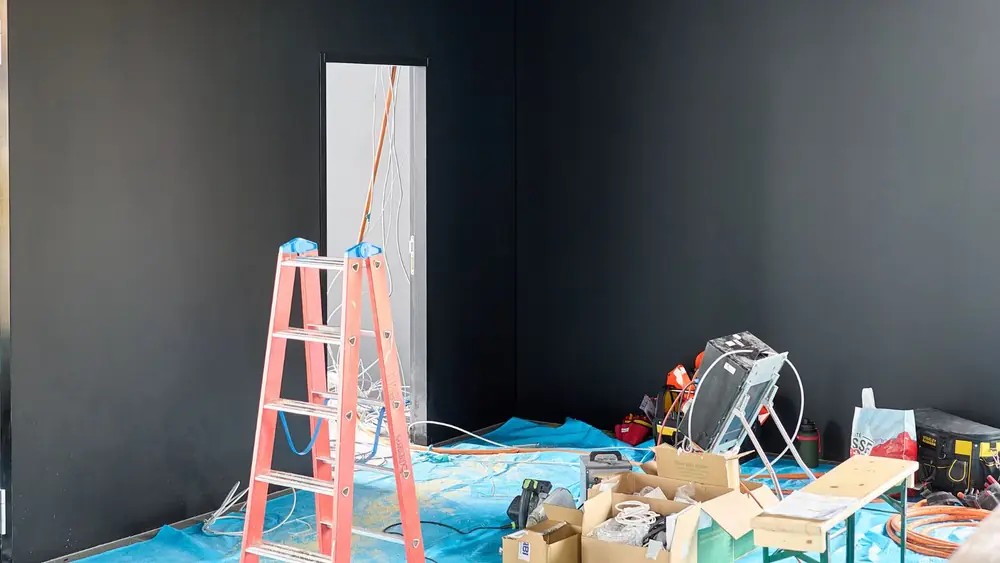 Room prepared for repair with a ladder and plastic sheeting